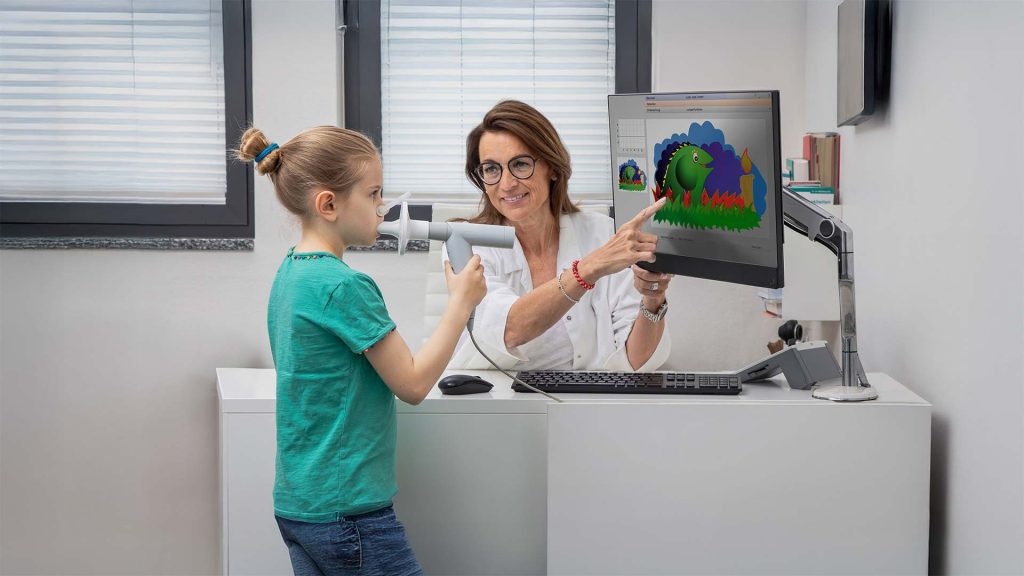 Spirometrische Untersuchung mit einem Kind, zur Unterstützung wird an einem Bildschirm die Kinderanimation "Schnaufi der Drache" gezeigt
