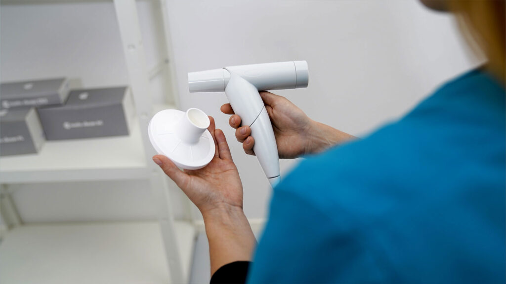 Medizinische Fachkraft in Praxisumgebung hält das custo spiro mobile in der einen und den Viren- und Bakterienfilter in der anderen Hand