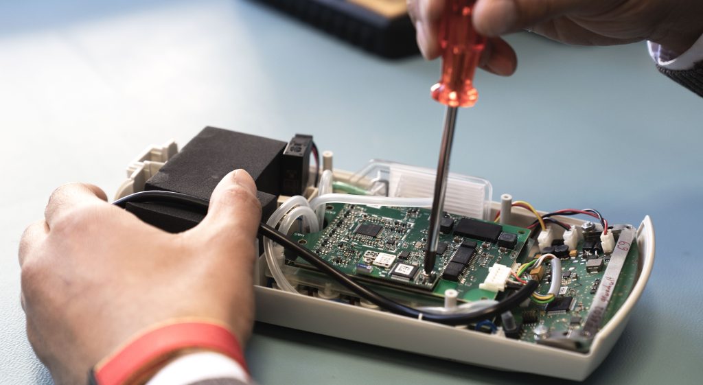 Manutenzione del custo cardio 400: componenti elettronici e scheda elettronica in un dispositivo medico, mani con attrezzi