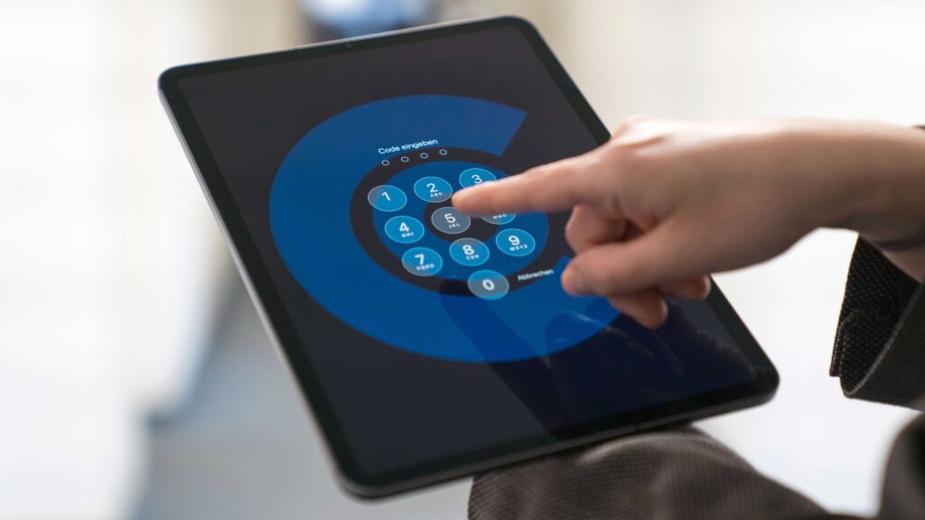 Person hält Tablet mit Sperrbildschirm zum Code eintippen in der Hand