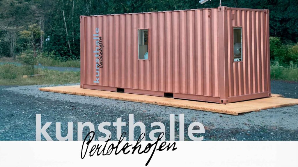 Un contenedor de barco de color naranja frente a un bosque, con la inscripción «Kunsthalle Pertolzhofen»